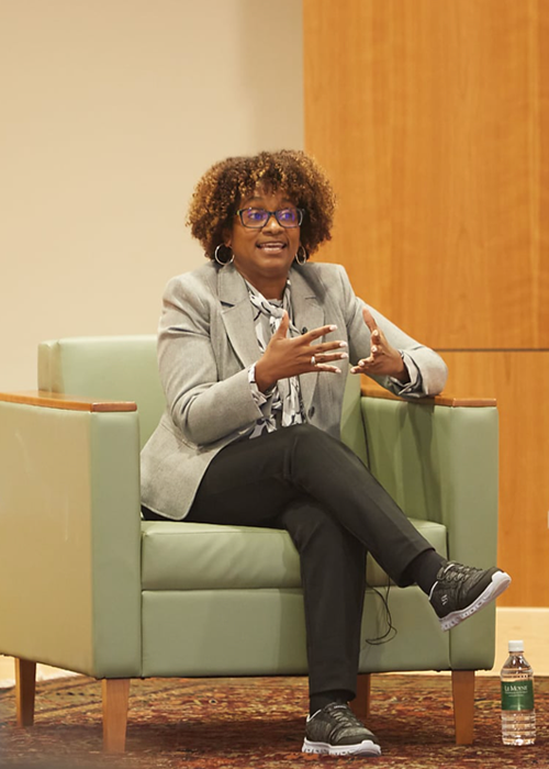Donna Hughes sitting in front of a chair speaking to an audience