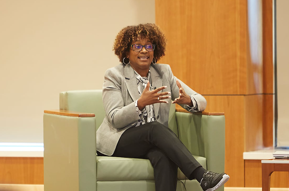 Donna Hughes sitting in front of a chair speaking to an audience